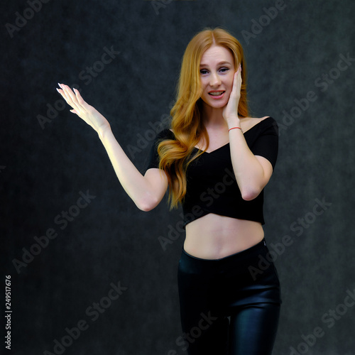 Concept portrait of a cute beautiful red-haired girl talking on a gray background in the studio