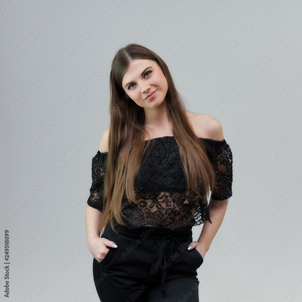 Concept portrait of a pretty beautiful brunette girl talking on a gray background in the studio standing Concept portrait of a pretty beautiful brunette girl talking on a gray background in the studio standing