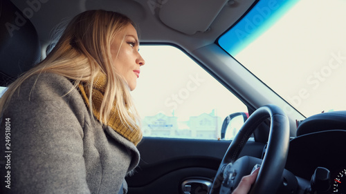 Young blonde woman driving car in in the daytime, close-up