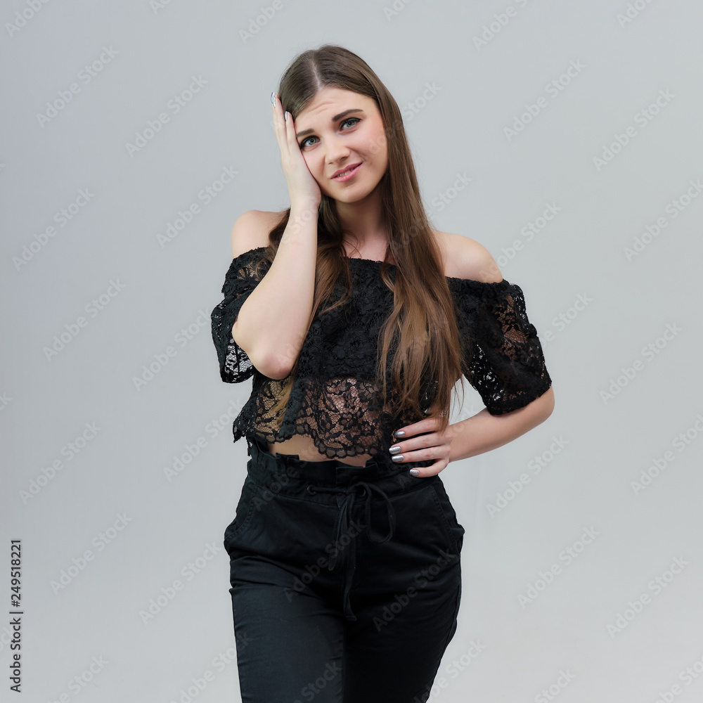 Concept portrait of a pretty beautiful brunette girl talking on a gray background in the studio standing Concept portrait of a pretty beautiful brunette girl talking on a gray background in the studio standing