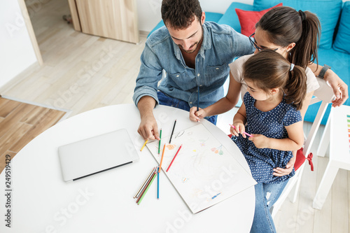 Father and mother teach daughter to draw.They sitting in living room.Education and family concept.
