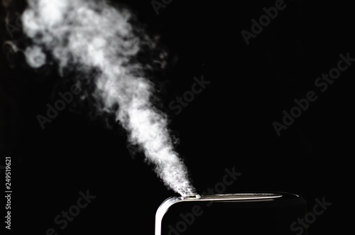 black humidifier on black background with white steam photo