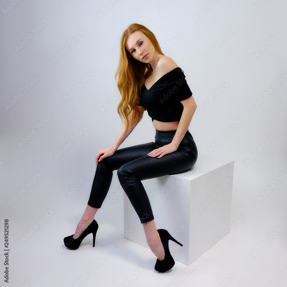 Concept portrait of a pretty beautiful red-haired girl talking on a gray background in the studio Concept portrait of a pretty beautiful red-haired girl talking on a gray background in the studio
