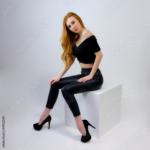 Concept portrait of a pretty beautiful red-haired girl talking on a gray background in the studio