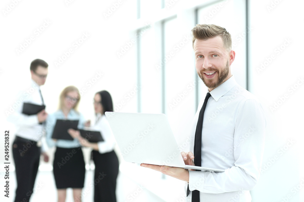 businessman with an open laptop standing in the hallway of the office. businessman with an open laptop standing in the hallway of the office.