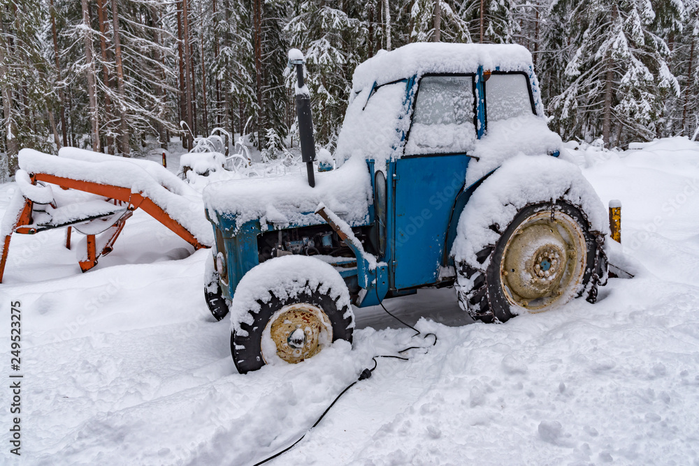 old blue tractor standing covered in snow old blue tractor standing covered in snow