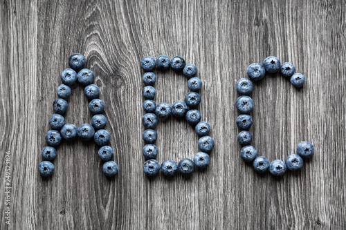 Letter A B C laid out of blueberry berries on a wooden background
