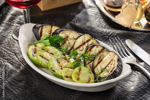 Grilled eggplant and zucchini slices on white plate served on the table
