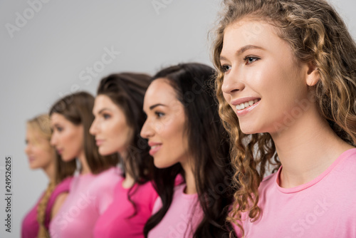 selective focus of cheerful girl with curly hair near young women isolated on grey