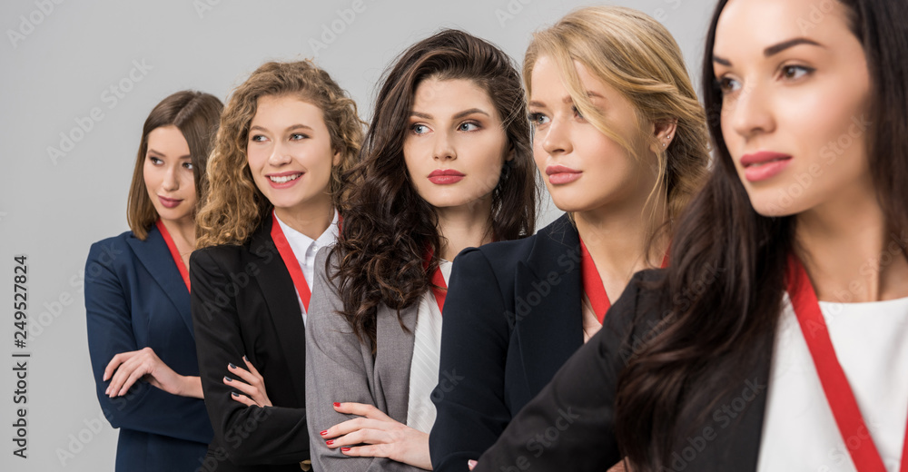 selective focus of beautiful young women standing with medals isolated on grey selective focus of beautiful young women standing with medals isolated on grey