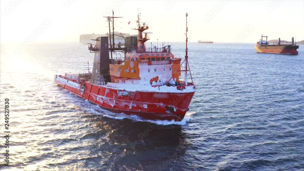 Aerial view of red fishing boat covered with frost sailing along the Eastern Bosphorus strait to Vladivostok. Sunny winter day. Russia Aerial view of red fishing boat covered with frost sailing along the Eastern Bosphorus strait to Vladivostok. Sunny winter day. Russia