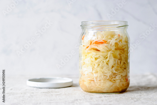 Glass jar filled with freshly made sauerkraut composed in daylight on white background