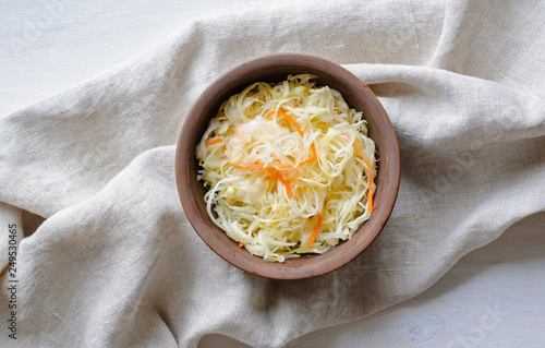 Cuadro en lienzo Top view of bowl of sauerkraut with cabbage on towel