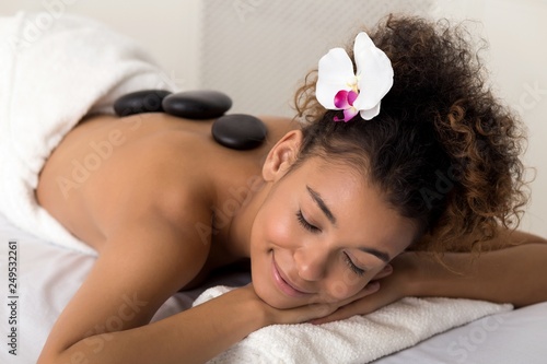 Woman enjoying hot stone massage at spa salon