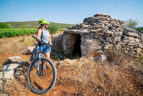 Woman traveler ride bicycle in the historic site on Stari Grad plain, UNESCO world heritage site in Hvar island, Dalmatia, Croatia photo