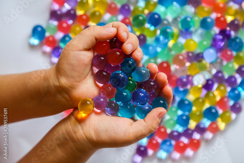 Colored balls of hydrogel in child's palms. Sensory experiences photo