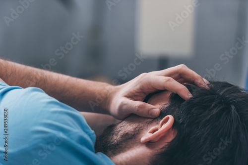 selective focus of grieving man covering face with hands and crying at home