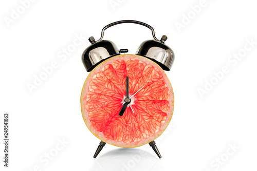 Grapefruiti slice on alarm clock, isolated on white background, fruit and vitamins diet at breakfast nutrition concept photo