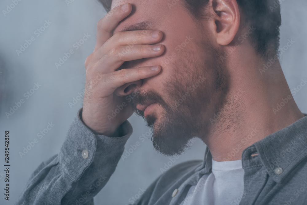 Fototapeta premium adult man covering face with hands and crying