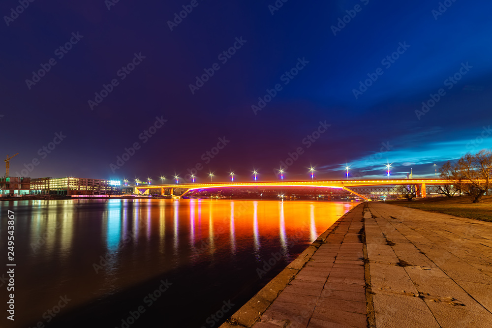 Belgrade, Serbia - February 10, 2019: The Gazela Bridge (Serbian: Most Gazela) is the most important bridge over the Sava river in Belgrade. A panorama of Belgrade by night with reflection in water.