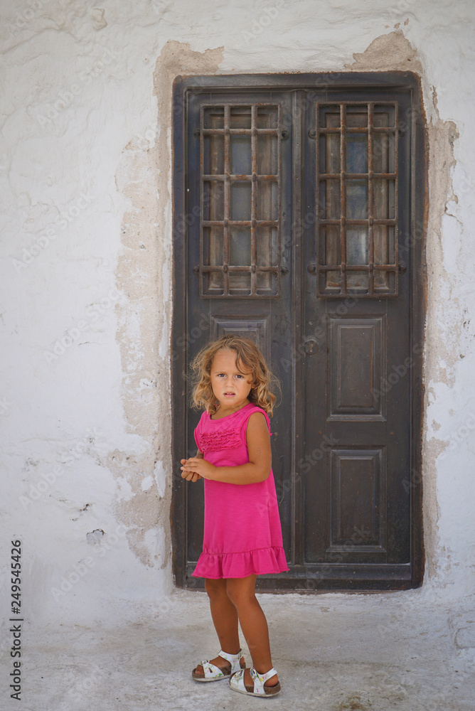 Small european tourist plays happy in the small town of Chora in Mykonos