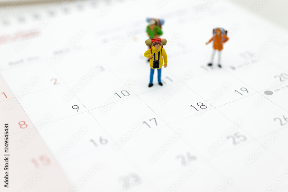 Miniature people, travelers standing on the calendar, mark date for traveling to destination. Used in the travel business concept. Miniature people, travelers standing on the calendar, mark date for traveling to destination. Used in the travel business concept.