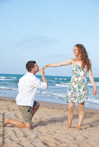 Loving couple on sea sandy beach - a man making decloration of love. Happy family spend their vacation on th sea.