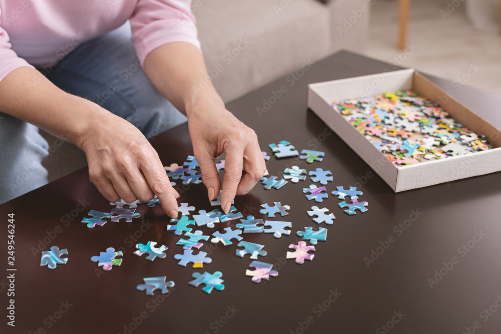 Elderly woman hands doing jigsaw puzzle closeup Elderly woman hands doing jigsaw puzzle closeup