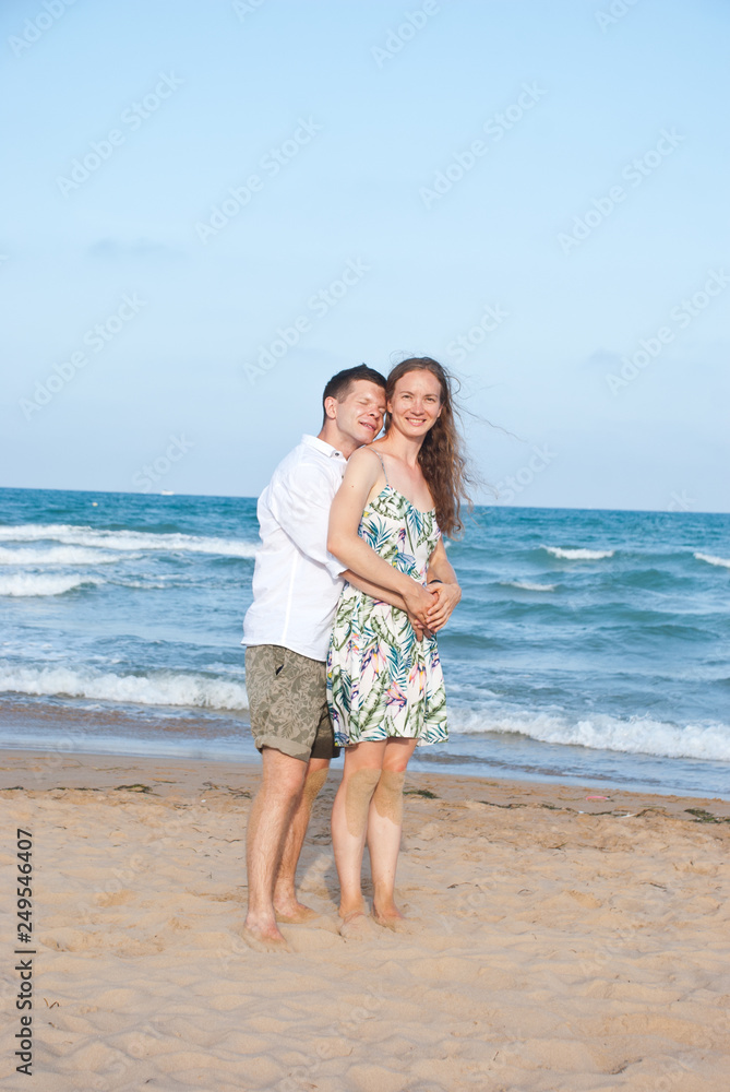 Image of couple hugging by the sea in Spain on their honeymoon. Happy family vacation.