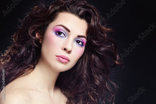 Portrait of young beautiful woman with long curly hair and fancy make-up