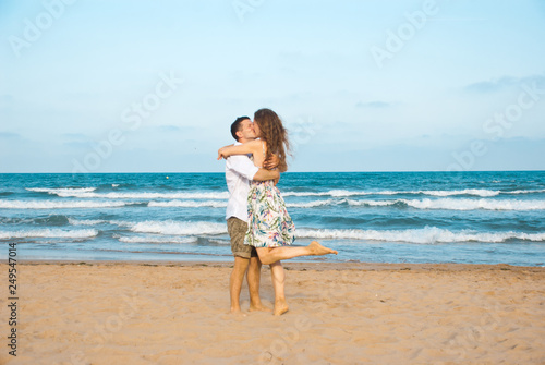 Euphoric young couple meeting and hugging on the sea beach. Horizontal shape, side view, copy space..Happy lovers.