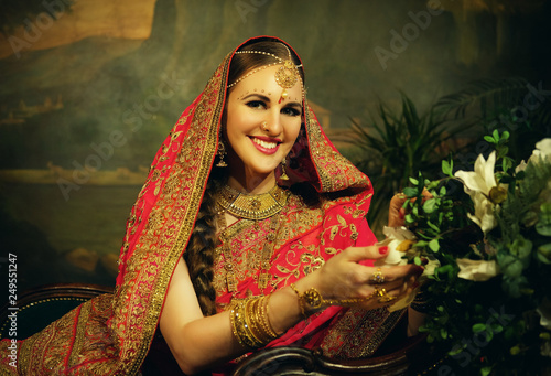 Portrait smiling of beautiful indian girl at home. Young woman model with golden jewelry set .