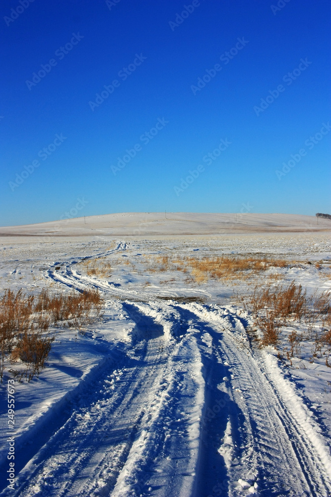 Country dirt road in a snowy field Country dirt road in a snowy field