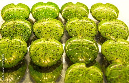 Cuadro en lienzo Handmade green candies in the form of monstera leafs on a show-window in shop