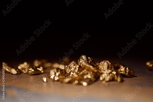selective focus of golden stones on grey and brown marble surface with blurred black background