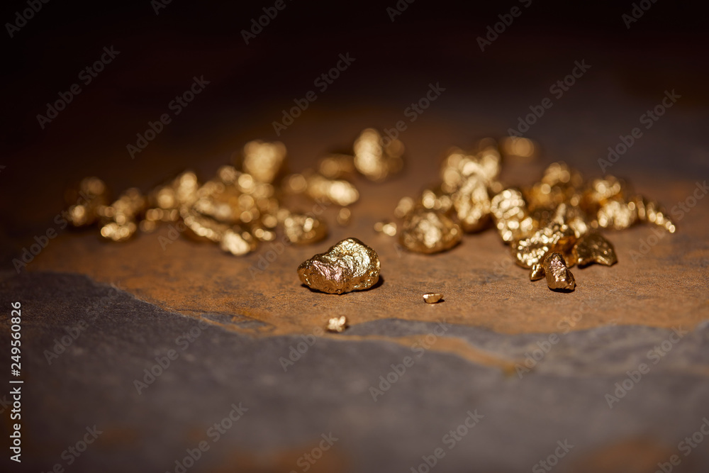 selective focus of golden stones on grey and brown marble surface with blurred dark background selective focus of golden stones on grey and brown marble surface with blurred dark background