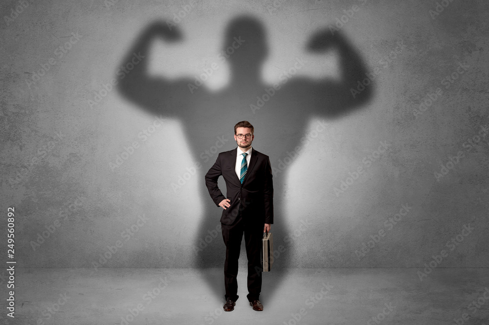 Obraz premium Lovely serious businessman standing with a muscular powerful shadow behind his back 