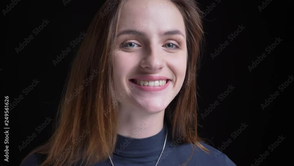 Close-up portrait of young and slim brunette caucasian girl smiling into camera on black background. Close-up portrait of young and slim brunette caucasian girl smiling into camera on black background.