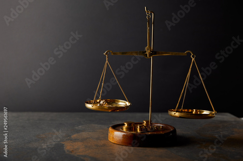 golden stones on scales on marble table and dark background
