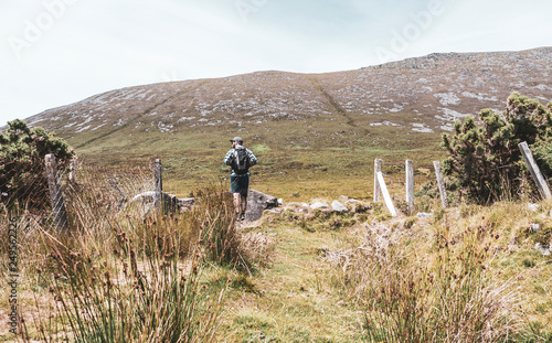 One man walking up a steep hill along the trek to the Megalithic Tomb in Slievemore, in Achill Island Ireland. photo