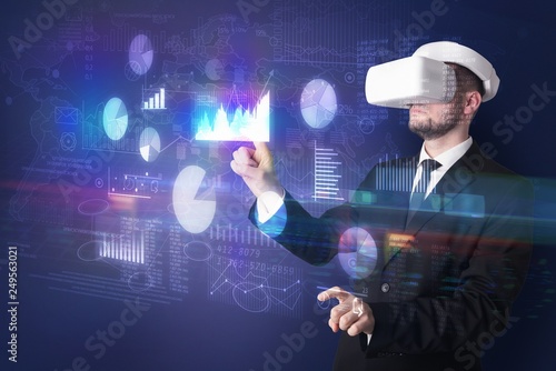 Elegant businessman in DJI goggles handling 3D reports and charts around him 