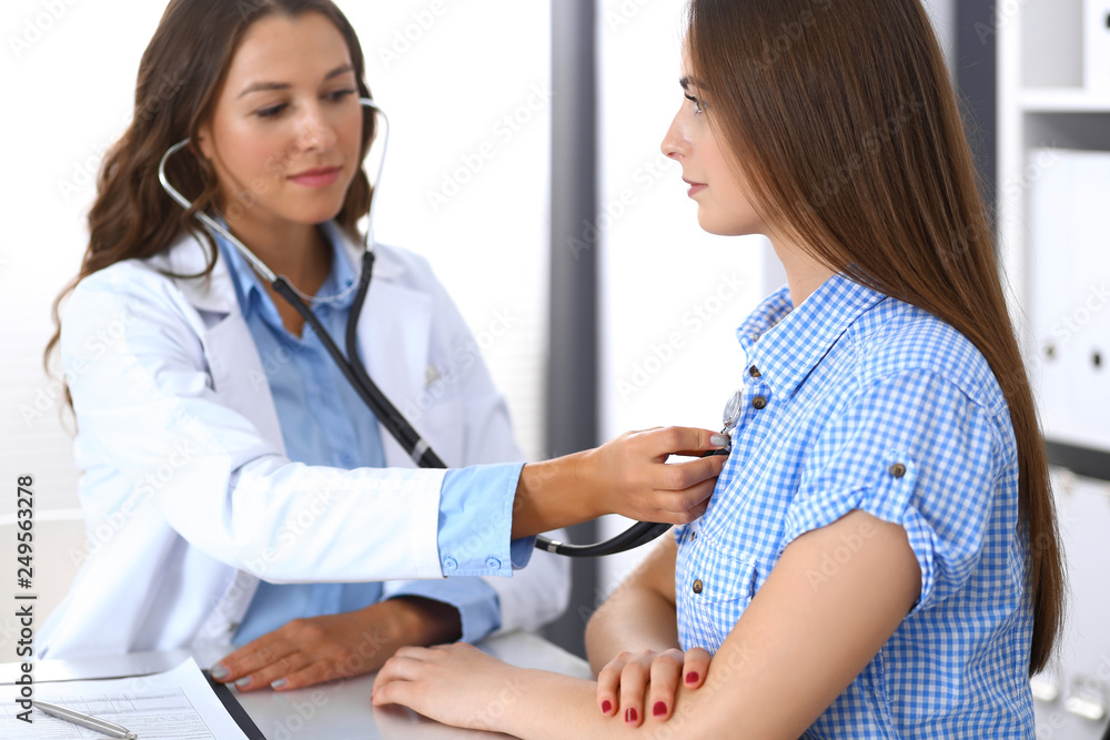 Doctor with a stethoscope in the hand examining her female patient. Health care, cardiology and medicine concepts Doctor with a stethoscope in the hand examining her female patient. Health care, cardiology and medicine concepts
