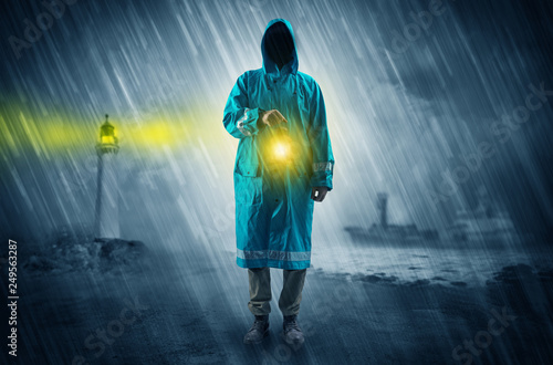 Man at the coast coming in raincoat with glowing lantern concept 