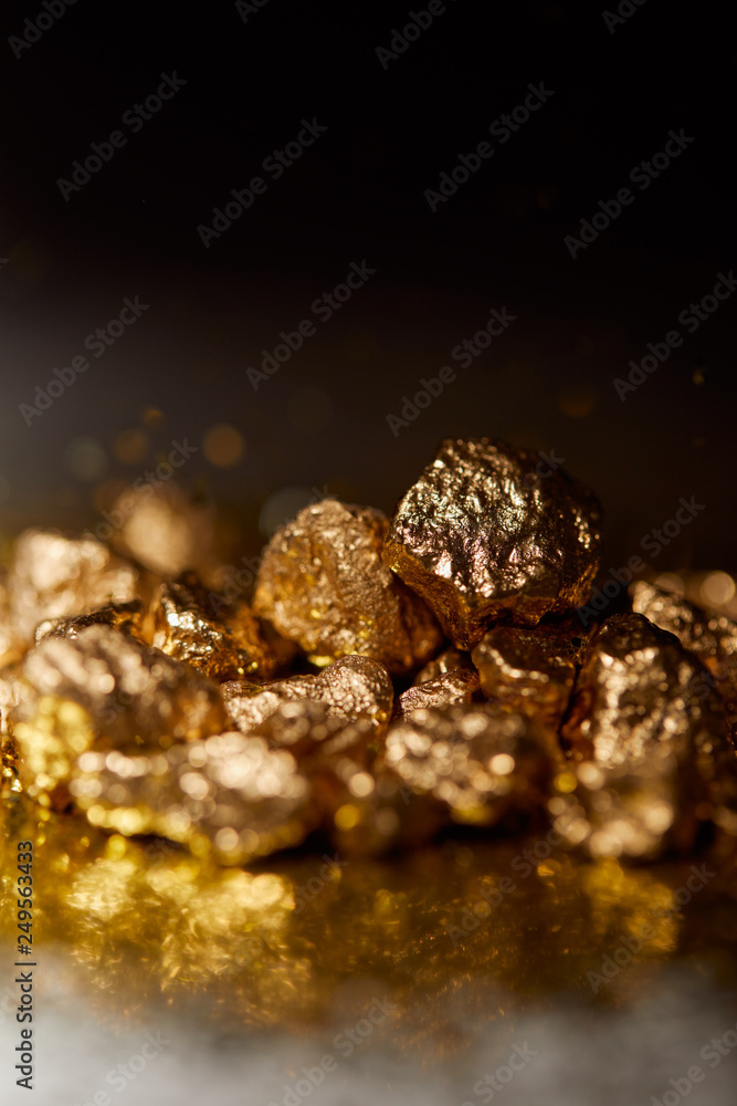 selective focus of golden stones on dark sparkling surface and black background
