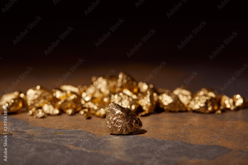 selective focus of golden stones on marble and black blurred background selective focus of golden stones on marble and black blurred background