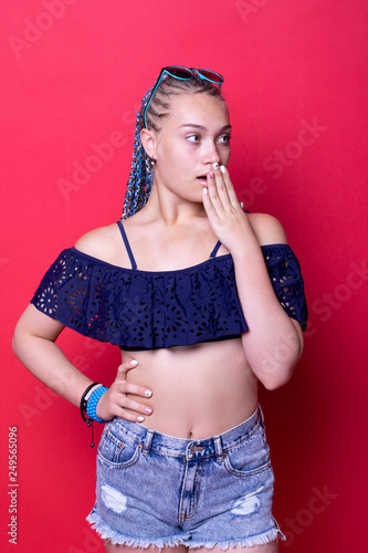 A teenage girl with bright blue dreadlocks wearing a stylish crop top, standing indoors