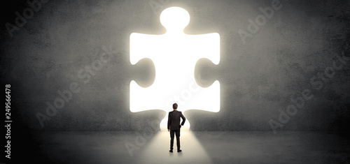 Businessman  standing and looking to a big puzzle piece
