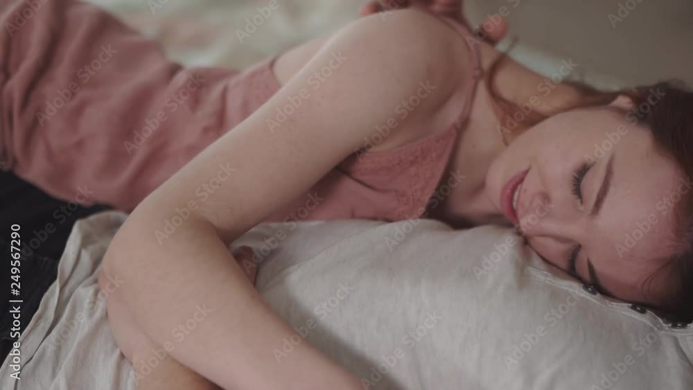 Pretty woman in pink night dress lying on chest of her boyfriend, holding his hand and touching his body gently close up. Loving couple rest at home together. Leisure of young family. Pretty woman in pink night dress lying on chest of her boyfriend, holding his hand and touching his body gently close up. Loving couple rest at home together. Leisure of young family.
