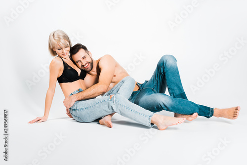 man and woman posing in underwear and jeans on grey