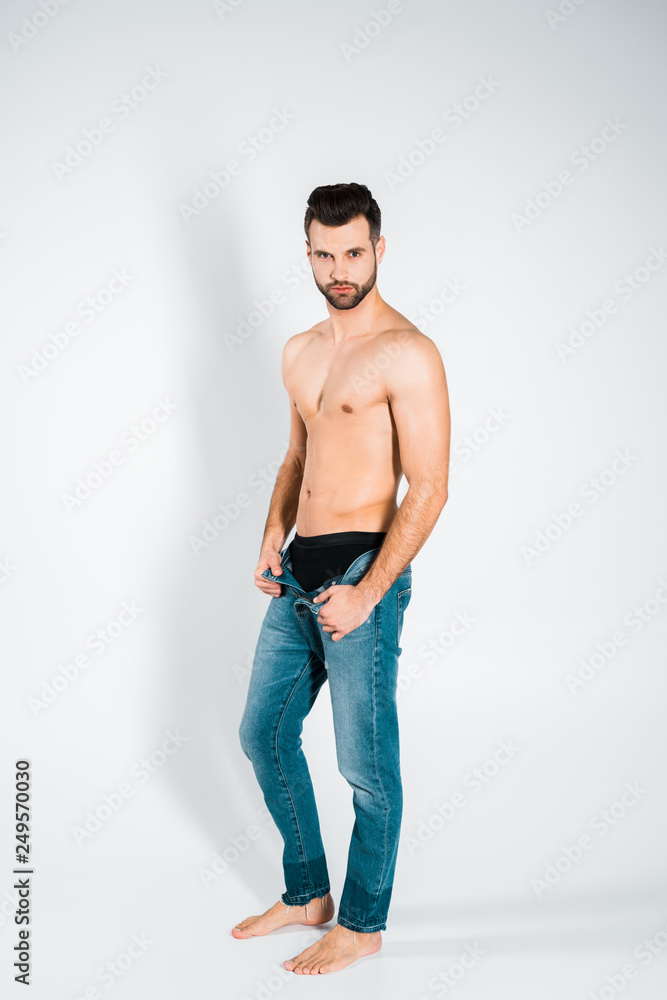 handsome bearded man in jeans posing on grey handsome bearded man in jeans posing on grey